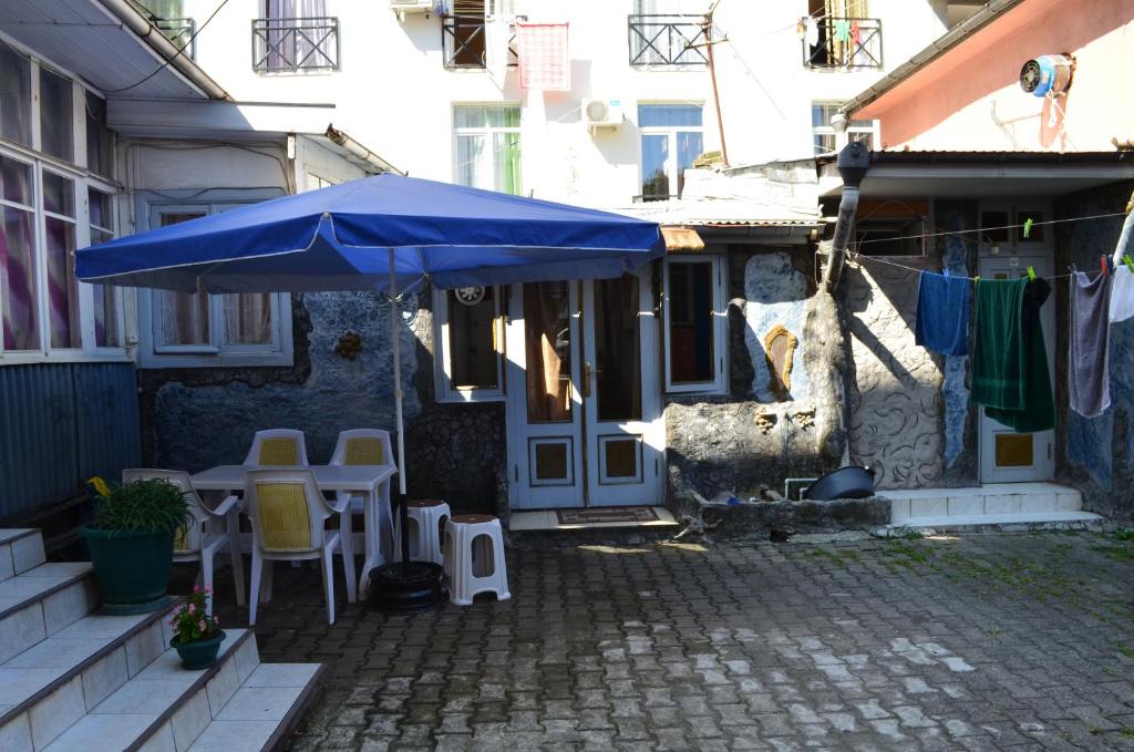 une terrasse avec un parasol bleu, une table et des chaises dans l'établissement TJ+ Hostel, à Batoumi