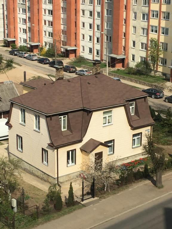 a large white house with a brown roof on a street at AV Apartment in Rēzekne