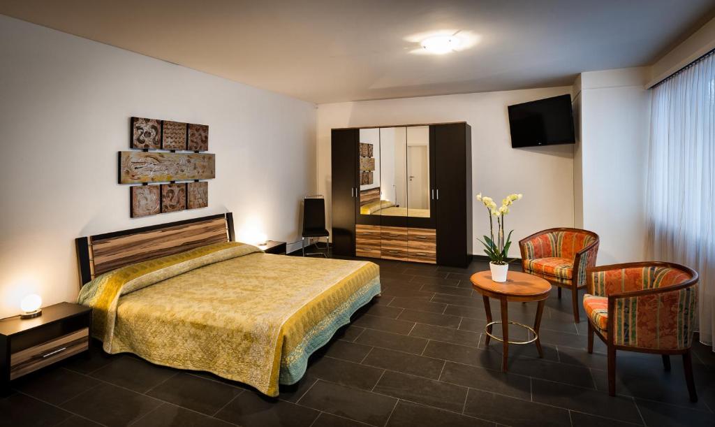 ein Hotelzimmer mit einem Bett, einem Tisch und Stühlen in der Unterkunft Residenze dell'Angelo in Locarno