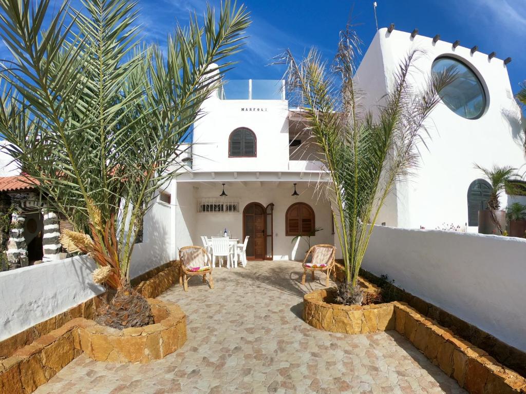 un edificio blanco con palmeras delante en Apartamento Playa de la Concha, en Cotillo