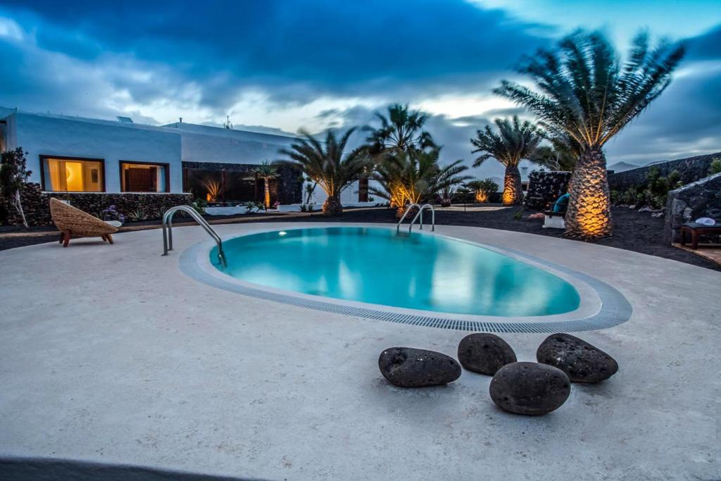 a swimming pool with rocks next to a house at Los Lirios Hotel Rural - Adults Only in Tías