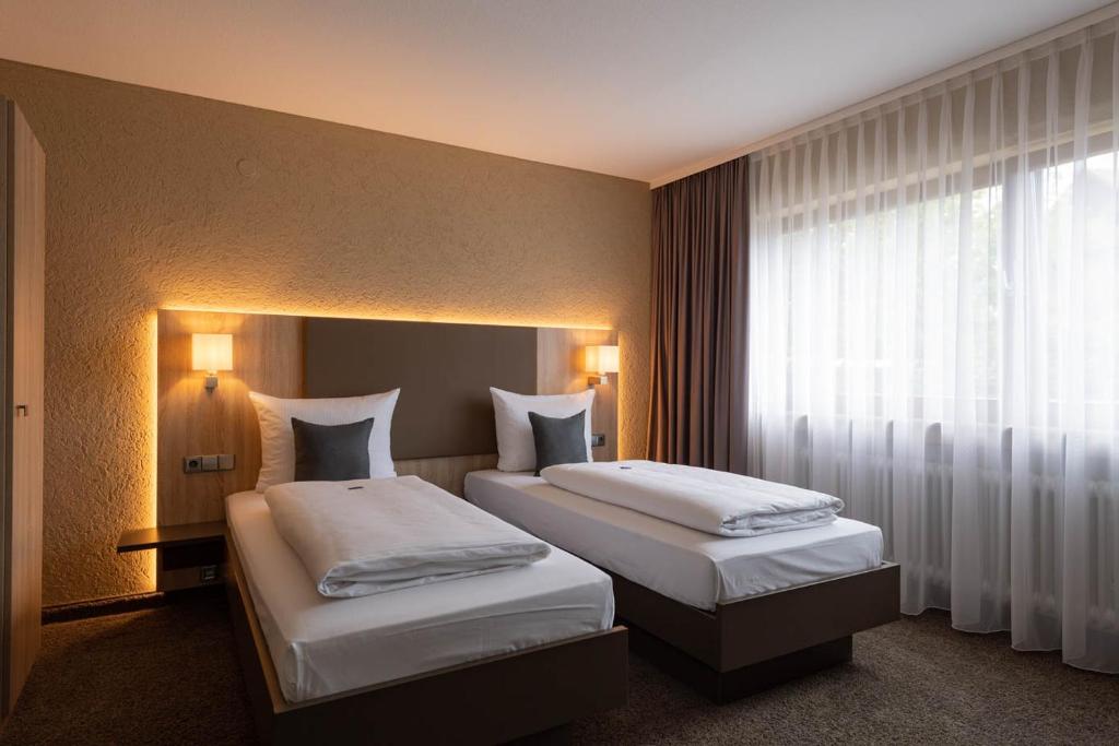 DonzdorfにあるGästehaus Becherのベッド2台と窓が備わるホテルルームです。
