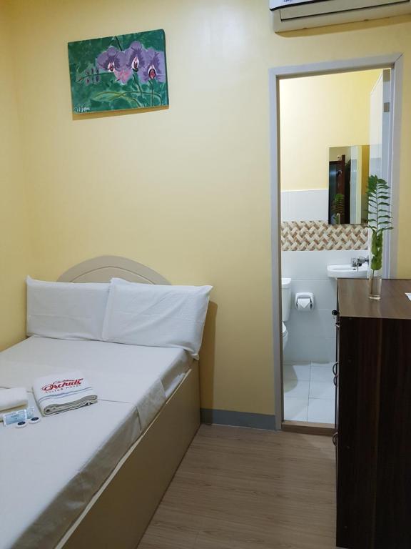 Habitación con cama y baño con espejo. en B&S Orchids suites hotel, en Dipólog