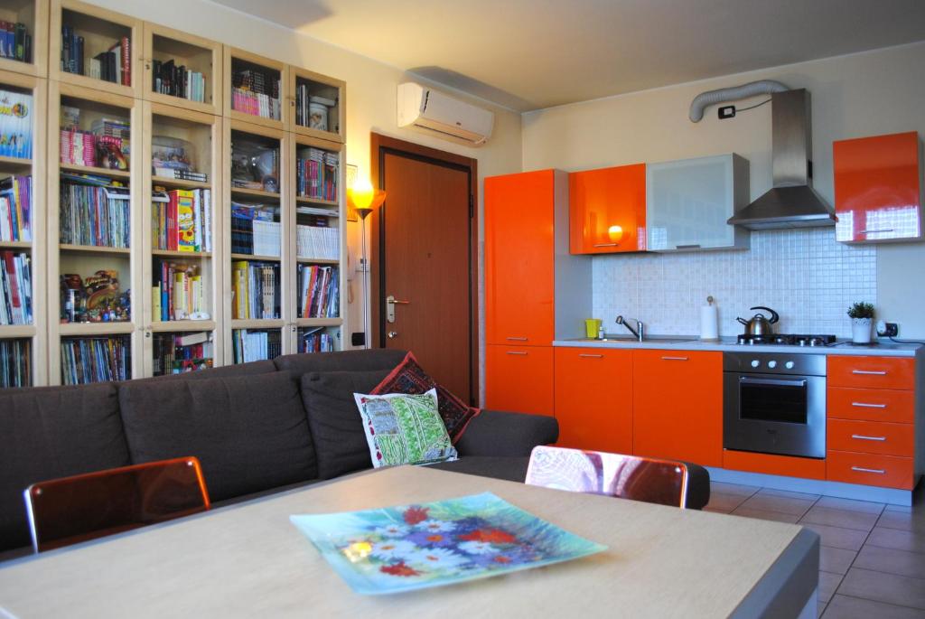 sala de estar con mesa y cocina con armarios de color naranja en Bnbook - Volta Fiera Milano, en Rho