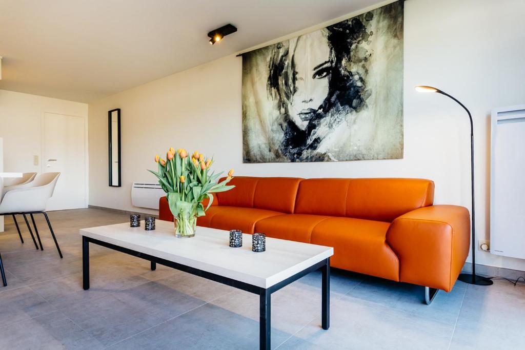 ミッデルケルケにあるHoliday Home Jonckershofのリビングルーム(オレンジカウチ、テーブル付)