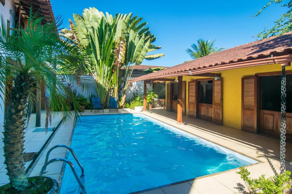 a swimming pool in front of a house with palm trees at Pousada Acquarela in Paraty