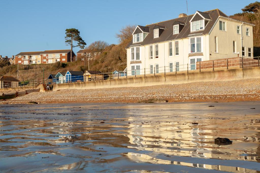 a house on the beach with its reflection in the water at Pier View Apartment in Totland
