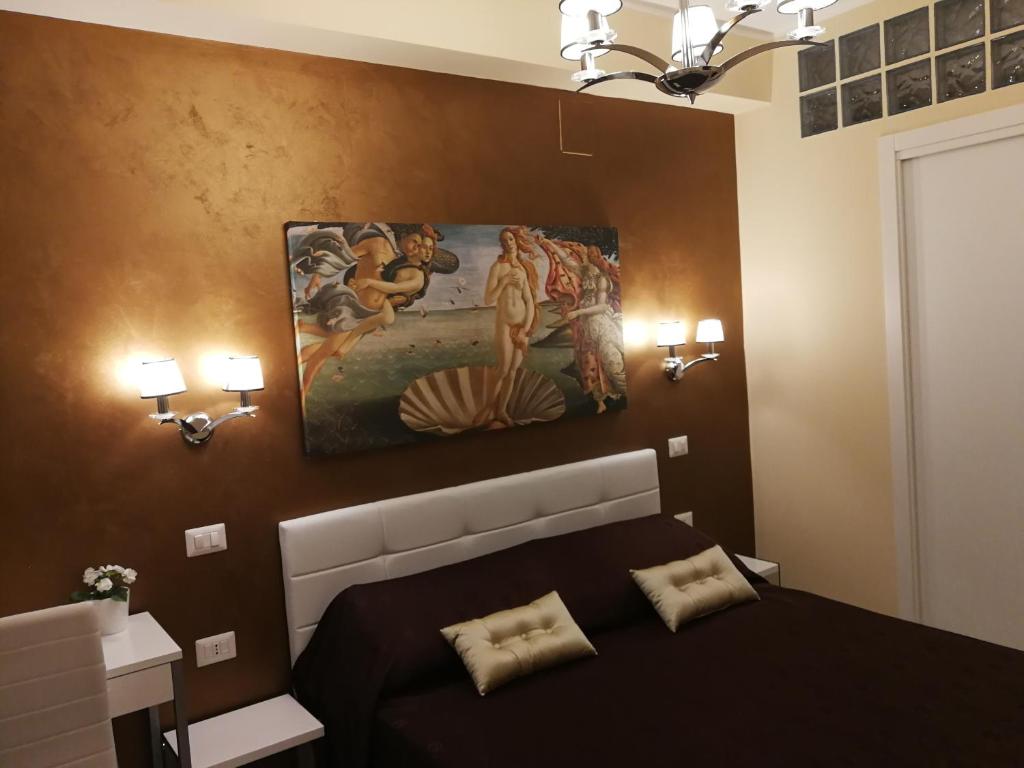 a bedroom with a bed with a painting on the wall at B&B Il Mare degli Dei in Letojanni