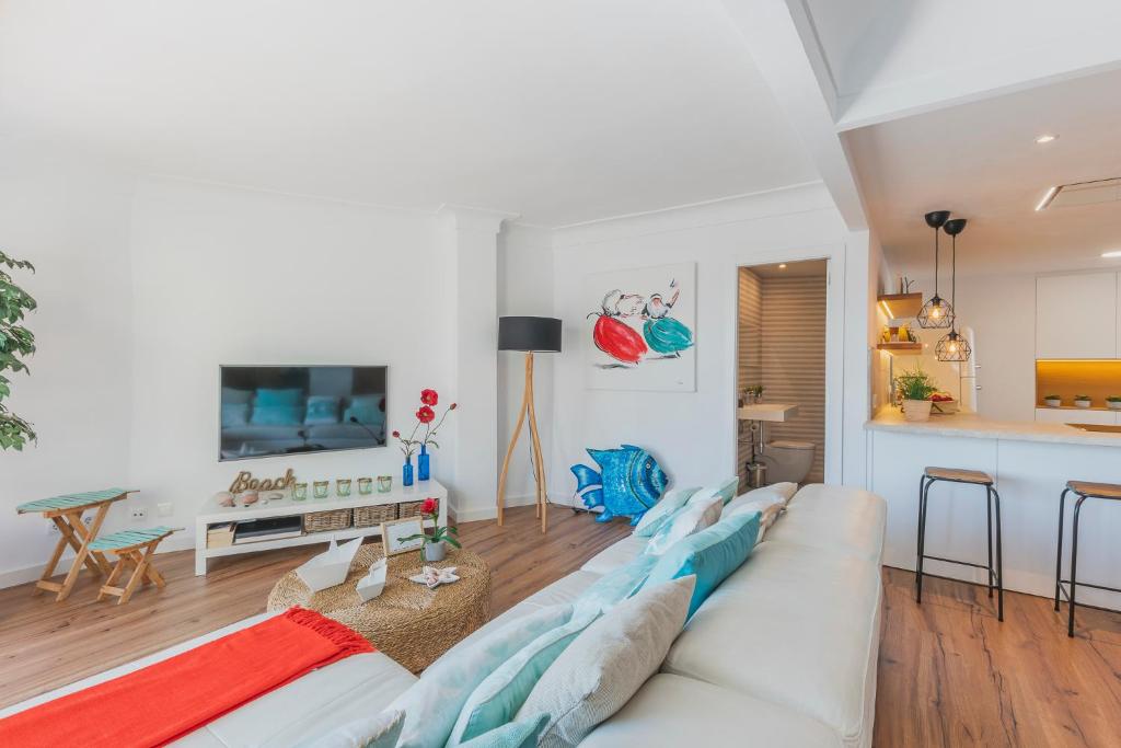 a living room with a white couch and a kitchen at YupiHome Mariners Apartment in Alcudia