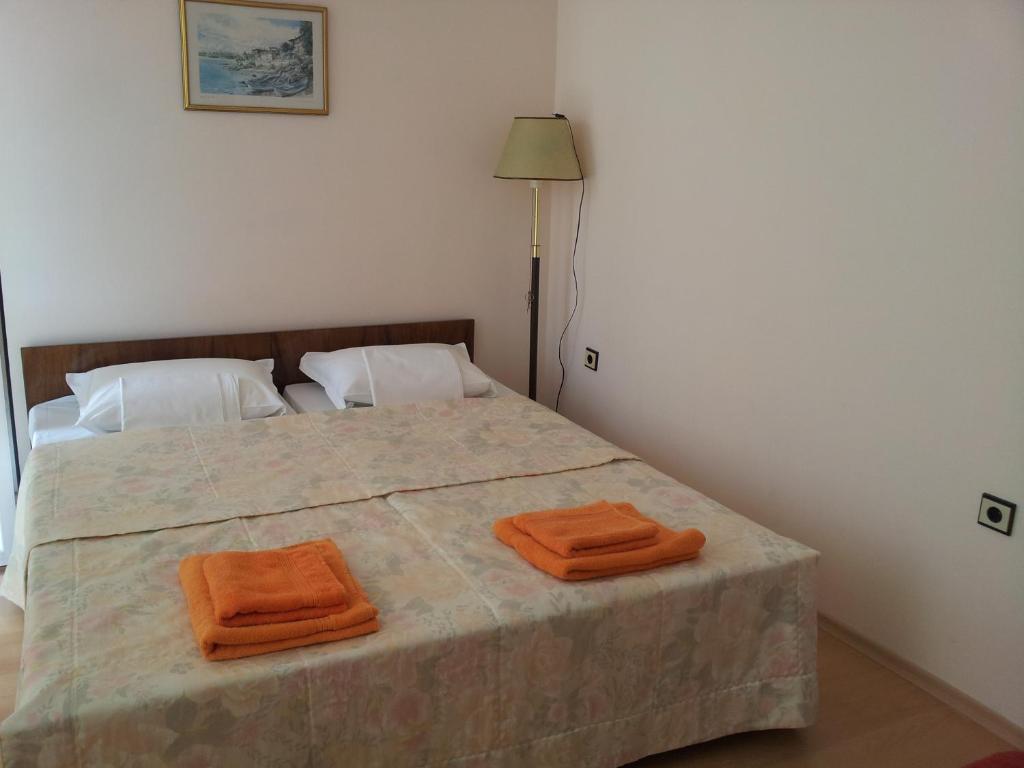 a bedroom with a bed with two orange towels on it at The House Next to the Beach in Sozopol