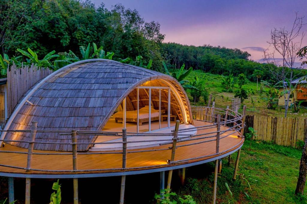 ein rundes Kuppelhaus mit einer Holzterrasse auf einem Hof in der Unterkunft Jaiyen Eco Resort in Ko Yao Noi