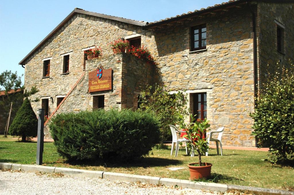 un edificio de piedra con una mesa y sillas delante de él en Casa Vacanze Vecchio Granaio en Magione