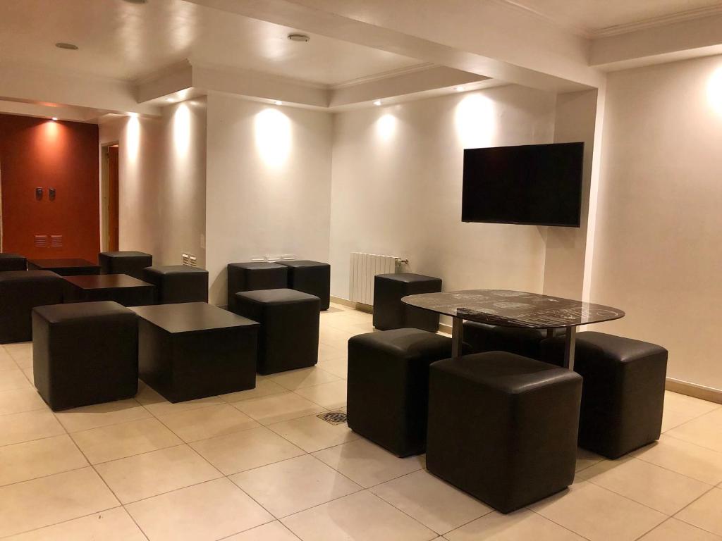 une salle d'attente avec une table, des tabourets et une télévision à écran plat dans l'établissement Hotel Petit, à Córdoba