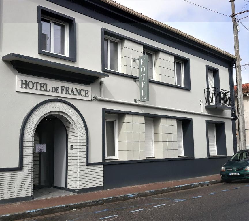 a building on a street with a car parked in front at Hôtel de France La Teste Arcachon in La Teste-de-Buch