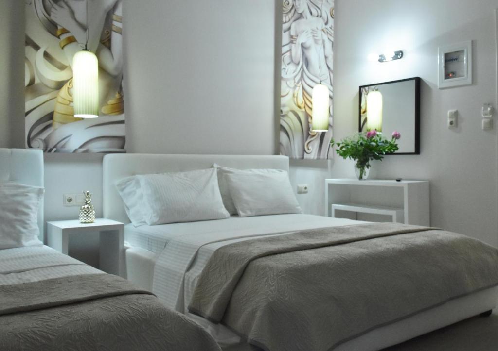 a white bedroom with two beds and a mirror at CROSS PLAZA in Stavros