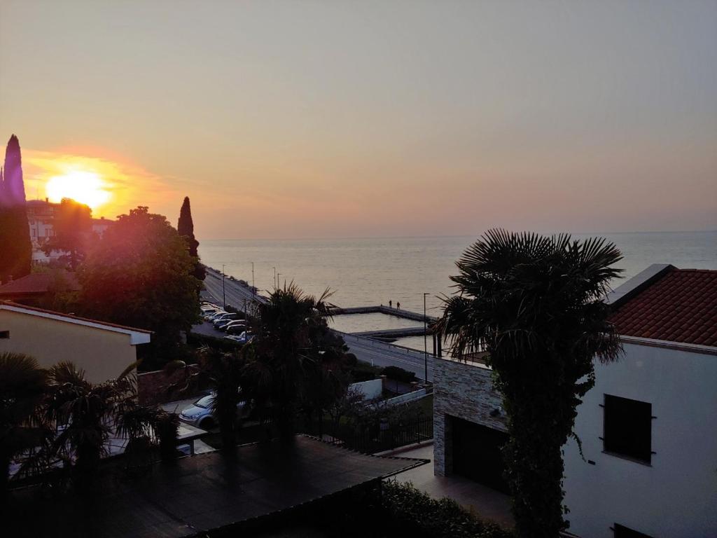 zachód słońca nad oceanem z palmami i budynkami w obiekcie Sobe Al Moletto w Koprze