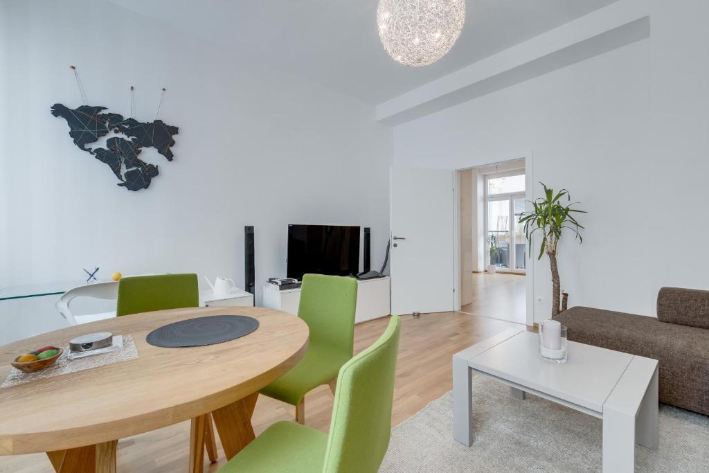 ein Wohnzimmer mit einem Holztisch und grünen Stühlen in der Unterkunft Modern Vienna in Wien