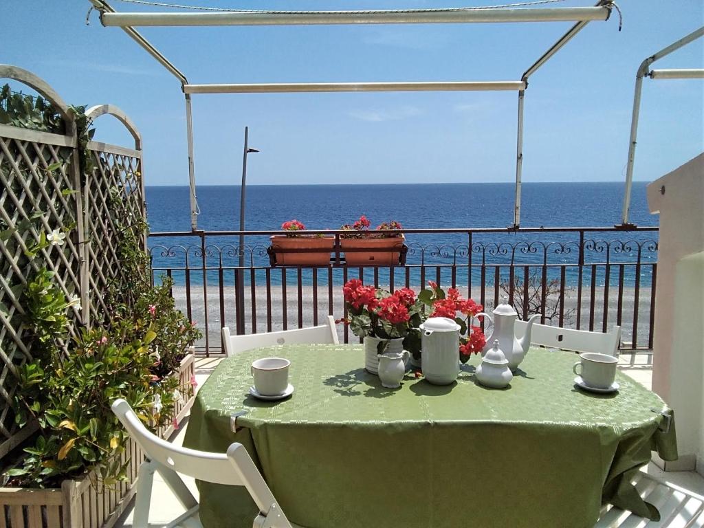 a table with flowers on top of a balcony with the ocean at CentroCittà Beach in Roccalumera