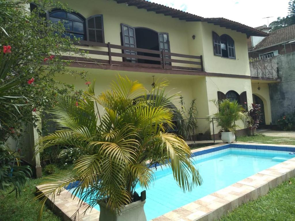a house with a palm tree next to a swimming pool at Pousada Casa Recanto da Serra in Petrópolis