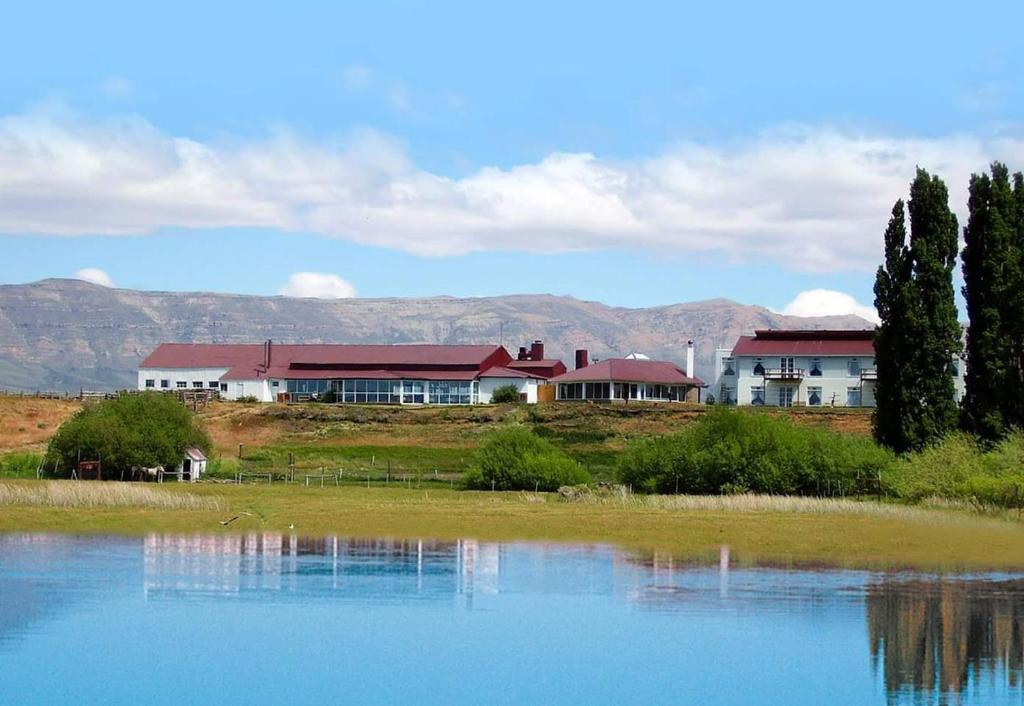 a house on a hill next to a body of water at Hostería El Galpón Del Glaciar in El Calafate