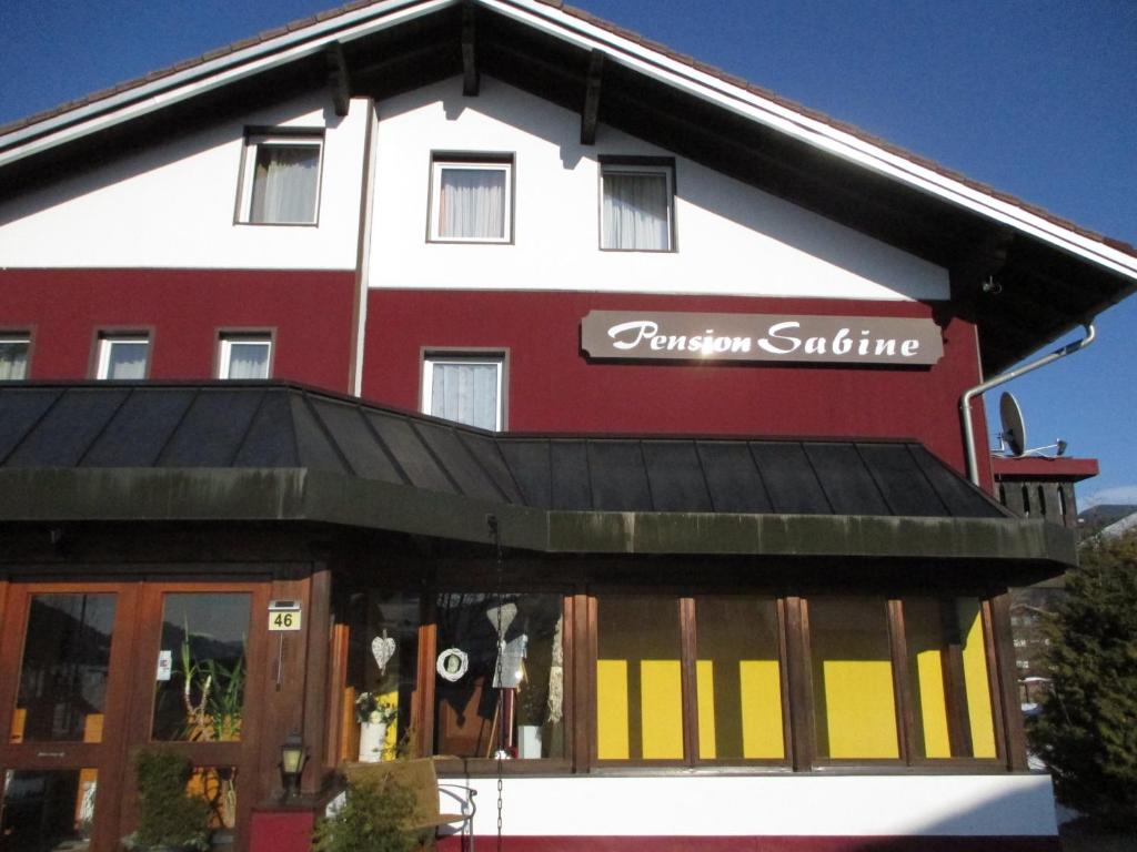um edifício vermelho e branco com um sinal em Pension Sabine em Oberstaufen