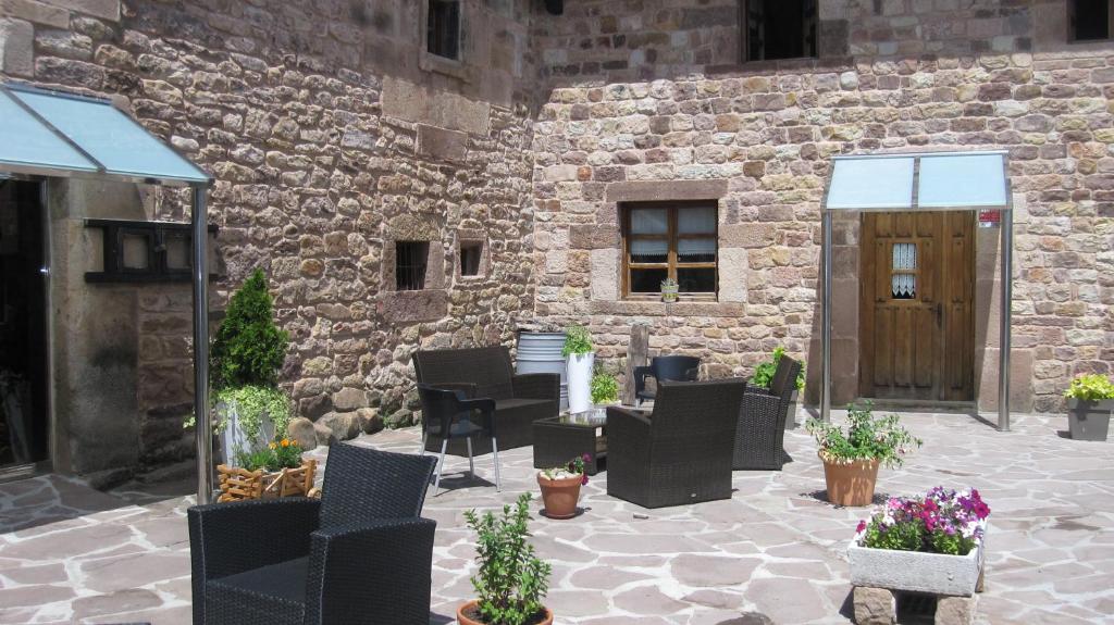 a patio with black chairs and a stone building at Posada Ormas in Ormas