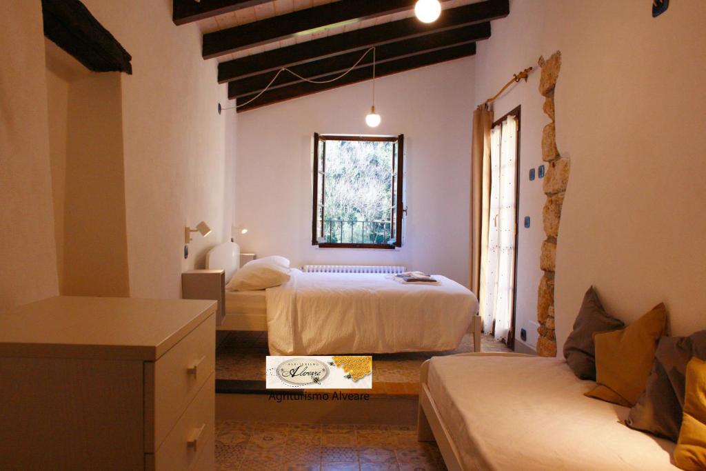 1 dormitorio con 2 camas, sofá y ventana en Agriturismo Alveare en Finale Ligure