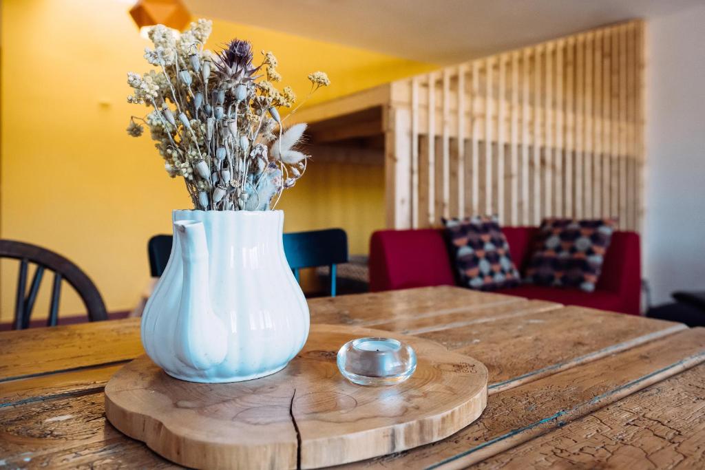 a white vase with flowers on a wooden table at PEDRA DOS CORVOS Beach House in Odeceixe