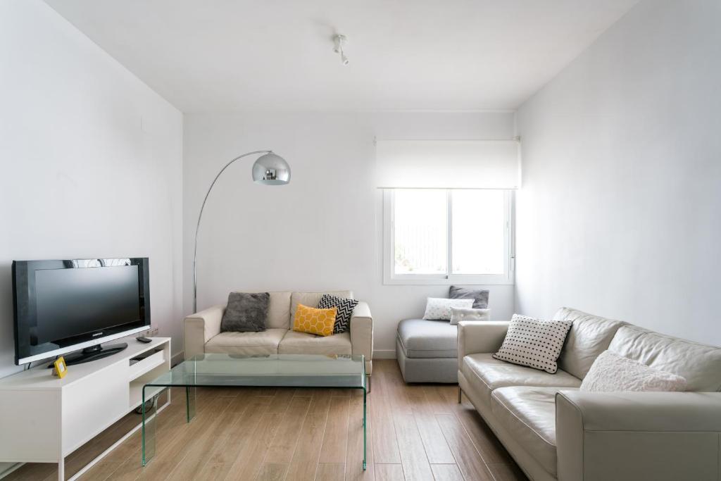 een woonkamer met een bank en een tv bij TRIANA 3 Bedrooms & 2 bath Parking Included in Sevilla