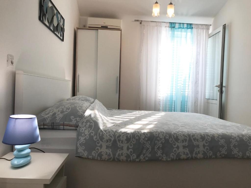 a bedroom with a bed with a blue lamp and a window at Apartments Milanović in Mali Lošinj
