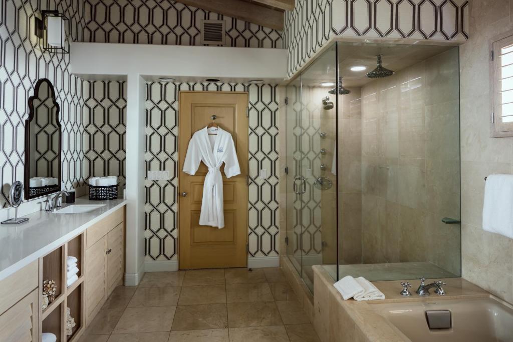 a bathroom with a shower and a robe hanging on the door at La Valencia Hotel in San Diego
