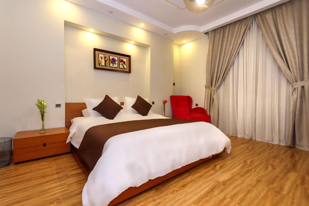 Arabella Residence في القاهرة: غرفة فندقية بسرير كبير وكرسي احمر