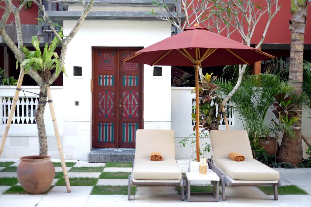 two chairs and an umbrella in front of a building at Amnaya Resort Kuta in Kuta