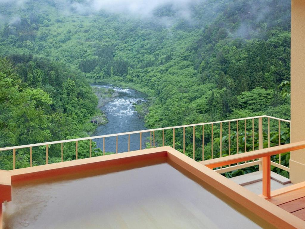 a balcony with a view of a river at Marumine Kanko Hotel in Aizuwakamatsu