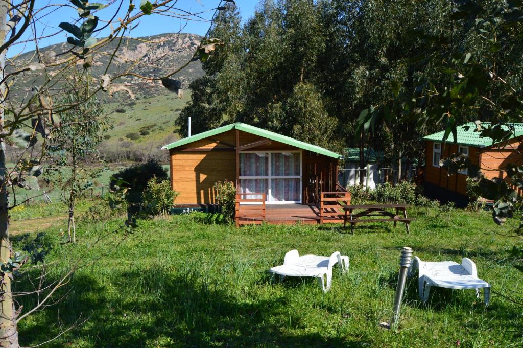 a small cabin with two white chairs in the grass at Camping du Soleil in Appietto