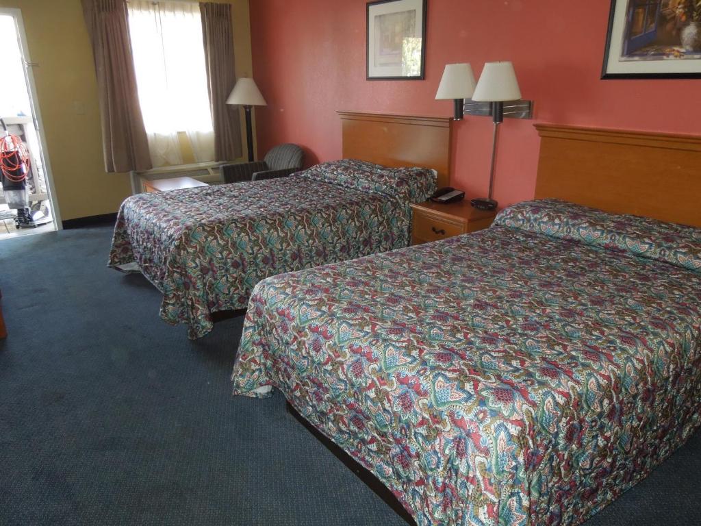 two beds in a hotel room with red walls at Kozy Inn in Columbus