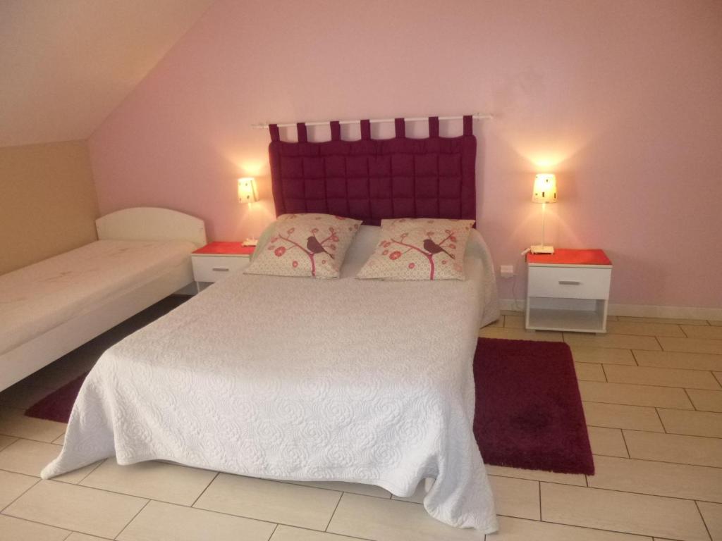 um quarto com uma cama branca e uma cabeceira roxa em Chambres d'Hôtes de Céline et David em Gahard