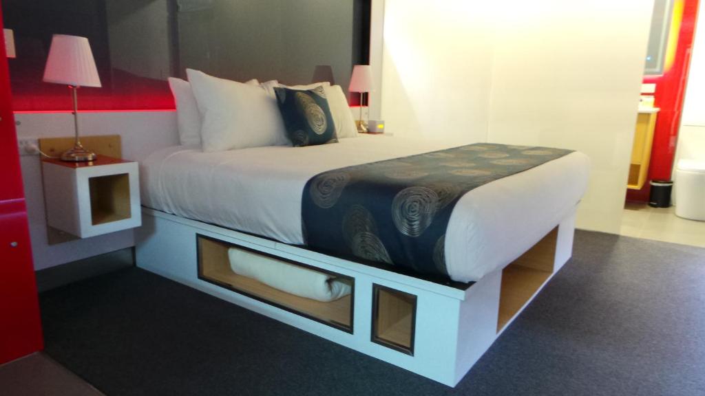 a bed in a hotel room with a bed frame with shelves at Room Motels Gympie in Gympie