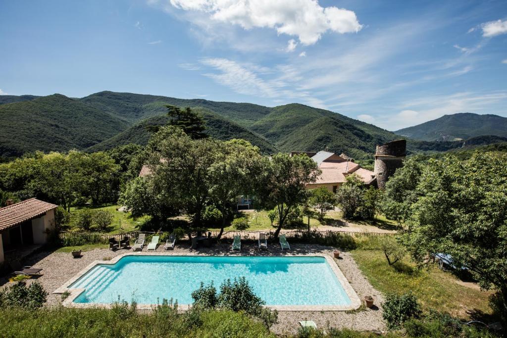 une piscine extérieure avec des montagnes en arrière-plan dans l'établissement Château de Colombières sur Orb, à Colombières