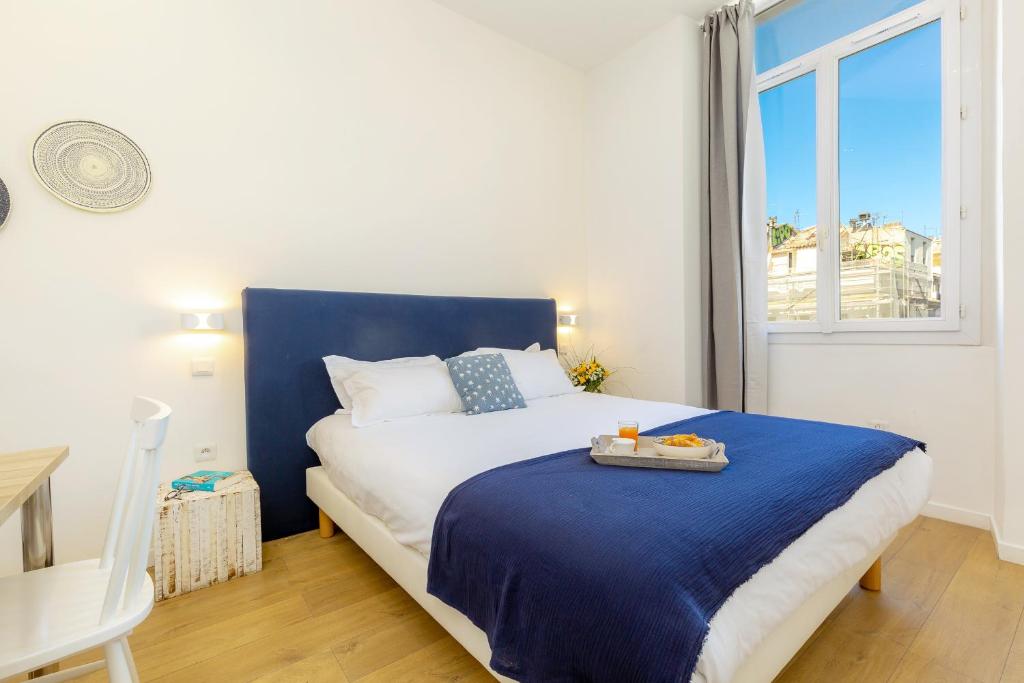 Un dormitorio con una cama azul y blanca y una ventana en Breteuil – Appart au Vieux Port en Marsella