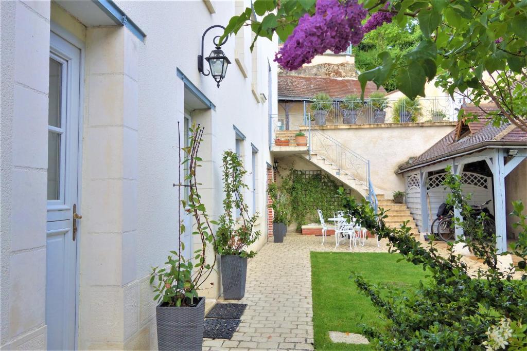 a courtyard of a white building with plants in pots at LA MAISON DE ROSE in Limeray