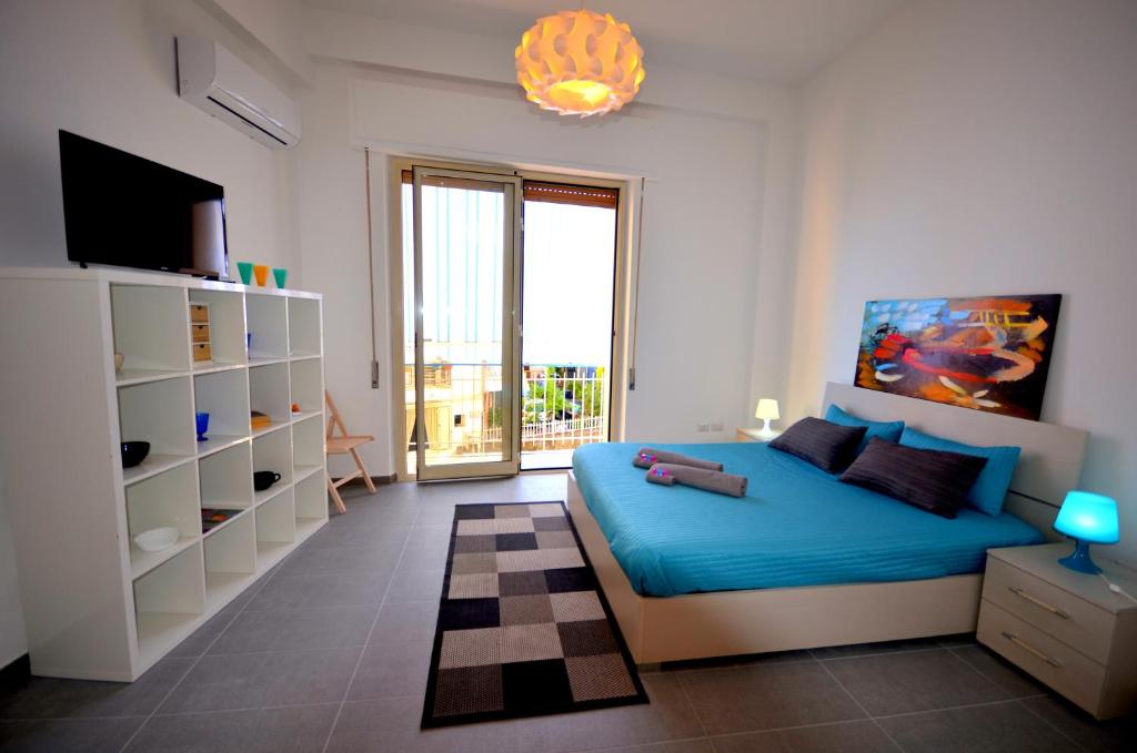 1 dormitorio con 1 cama azul y TV en Casa Maja, en Giardini Naxos