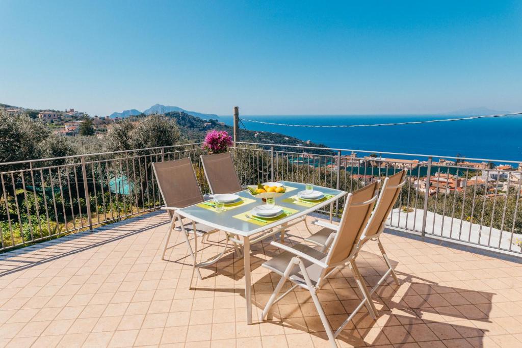 een tafel en stoelen op een balkon met uitzicht op de oceaan bij EverSun in Massa Lubrense