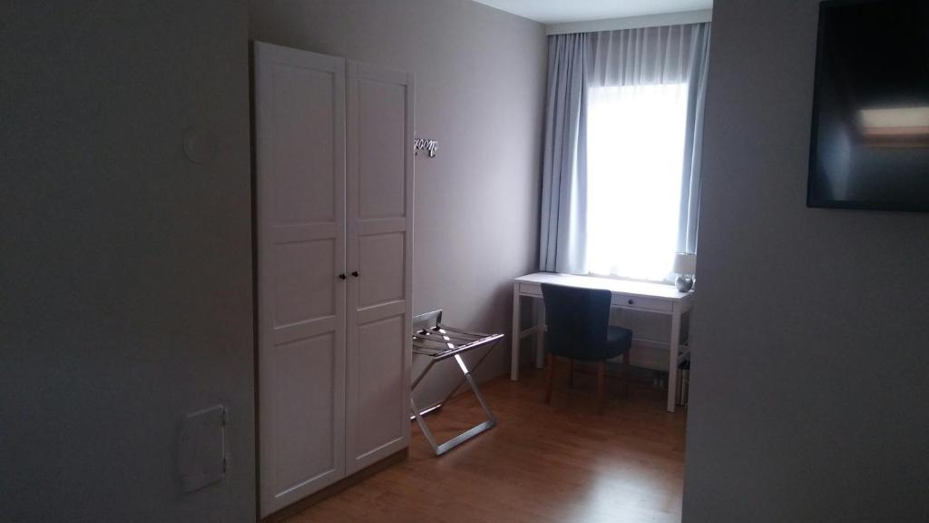 Zimmer mit einer Tür, einem Schreibtisch und einem Fenster in der Unterkunft Altstadtappartements Hartberg in Hartberg