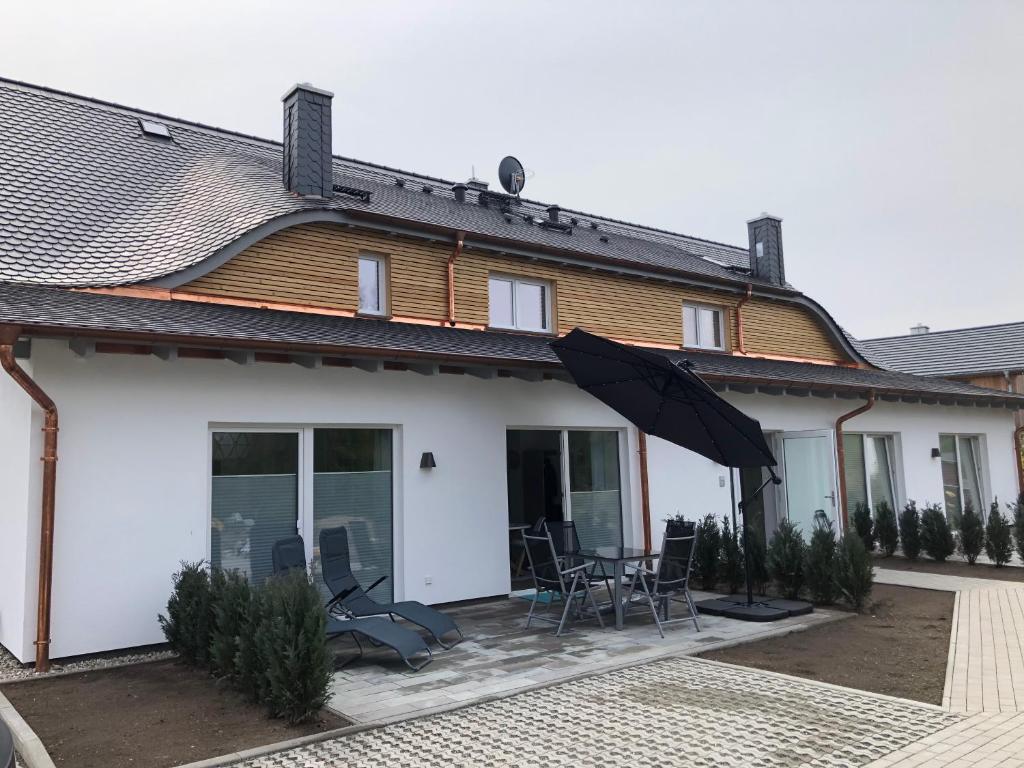 a house with an umbrella and chairs on a patio at Prerow „Seaside“-strandnah! in Prerow