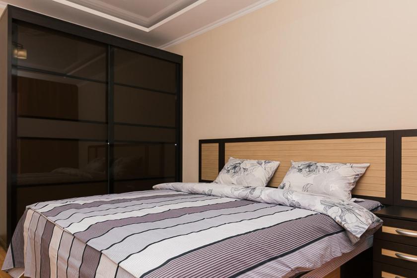 Schlafzimmer mit einem Bett mit einem Kopfteil aus Holz in der Unterkunft 14/3 вулиця Прокоф'єва in Sumy