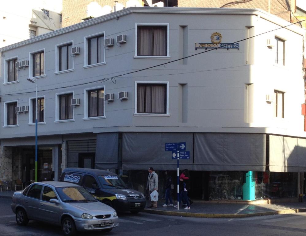 a white building with cars parked in front of it at Lorenzo Suites Hotel in San Miguel de Tucumán