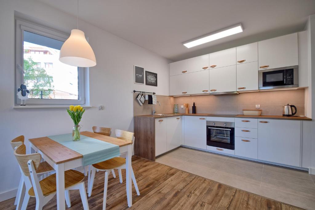 a kitchen with white cabinets and a table and chairs at Bursztyn 2 in Kołobrzeg