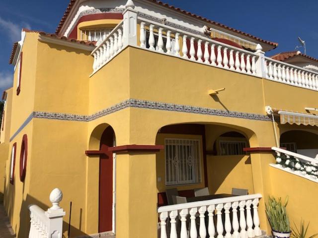 een groot geel huis met een wit balkon bij Macerana 1, Torreta III, Torrevieja in Torrevieja