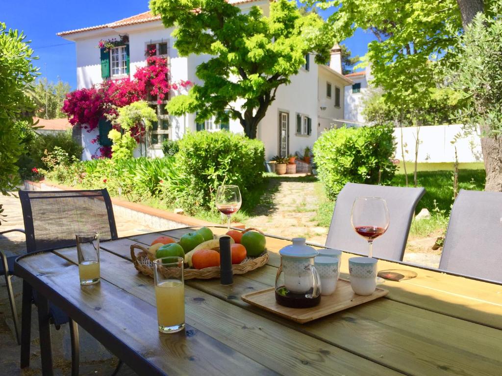 a wooden table with wine glasses and fruit on it at Cascais Seaside Garden Villa in Cascais